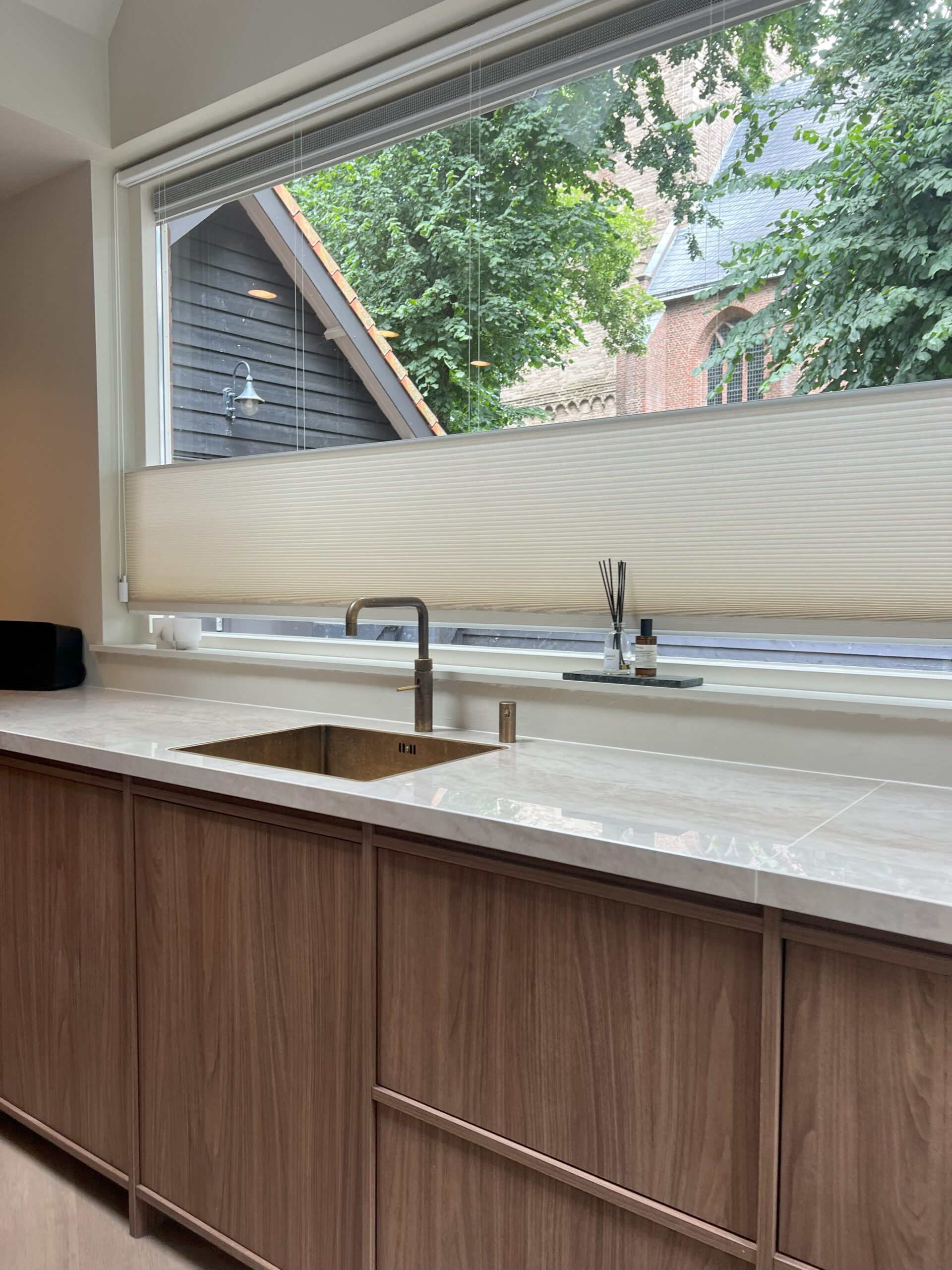 Dekton aanrechtblad met een japandi keuken eronder en een bronzen kraan en spoelbak erin